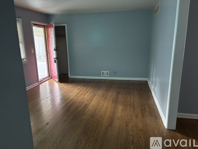 A room with wooden flooring and a red door.