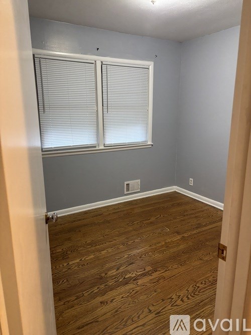 A room with wooden flooring and a window with blinds.