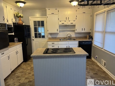 A kitchen with white cabinets and a black refrigerator.