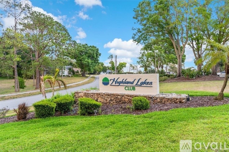 A sign for the Highland Lakes Club is surrounded by greenery.