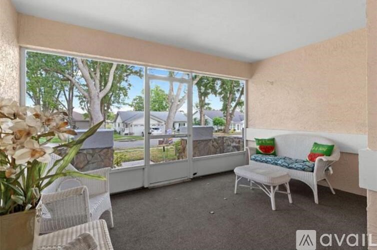 A sunny patio with a white sofa and chairs.