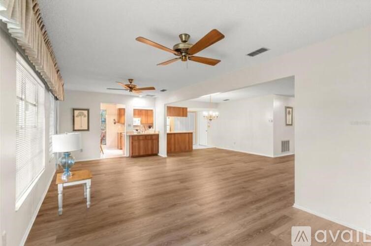 A spacious room with a ceiling fan and hardwood floors.