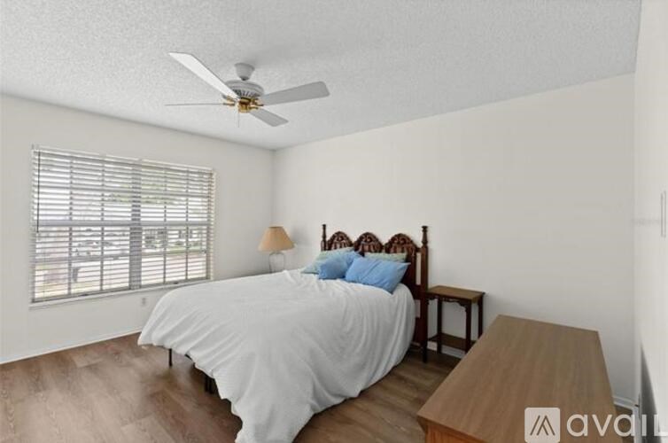 A bedroom with a bed, a ceiling fan, and a window with blinds.
