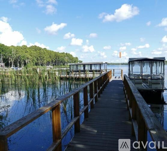 A wooden dock extends into a calm body of water with a boat docked at the end.