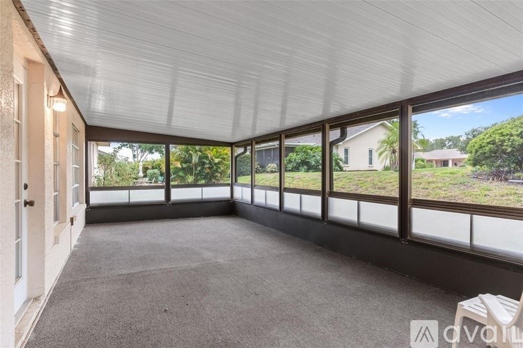 A sunroom with a carpeted floor and a ceiling fan.