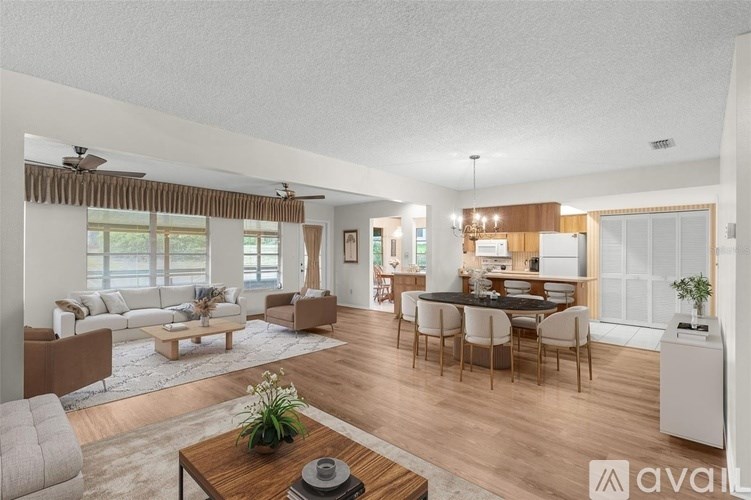 A modern living room with a dining area and kitchen in the background.