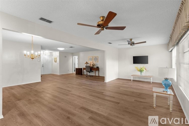 A spacious living room with wooden floors and a ceiling fan.