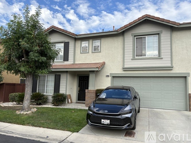 A black car is parked in front of a house with a garage.