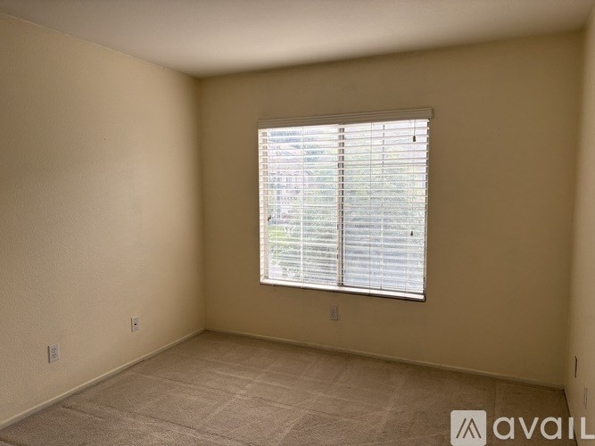 A room with a window covered by white blinds.