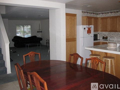 A kitchen with a table and chairs in the foreground and a refrigerator in the background.