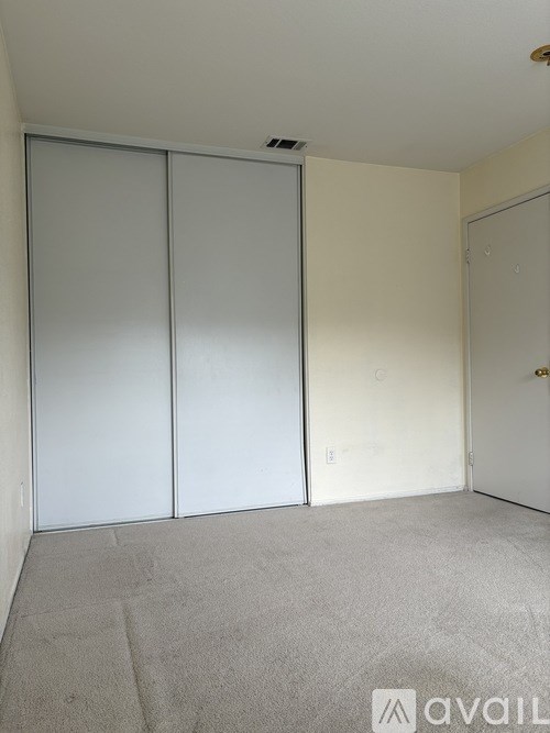 A room with a carpeted floor and a white door.