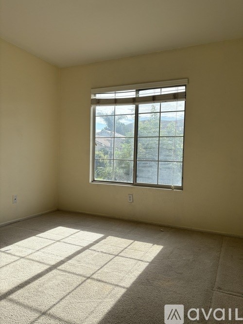 A room with a large window and a carpeted floor.