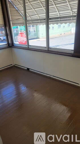 A room with a wooden floor and a window overlooking a stop sign.