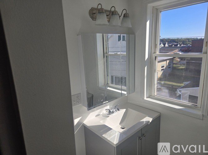 A bathroom with a sink, mirror, and window.