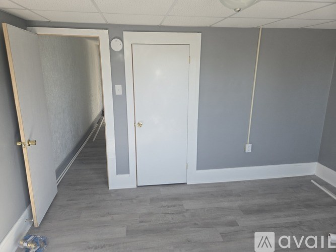 A room with a white door and a grey wall.