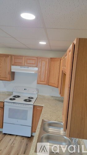 A kitchen with wooden cabinets and a white stove top oven.