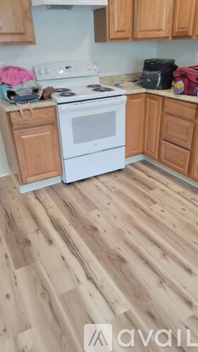 A kitchen with a white stove top oven and wooden floors.
