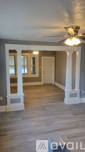 A room with a ceiling fan and wooden flooring.