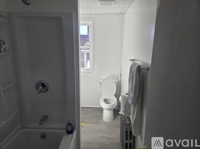 A bathroom with a toilet, a tub, and a window.