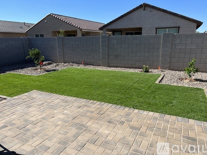 A backyard with a brick patio and a grey house.