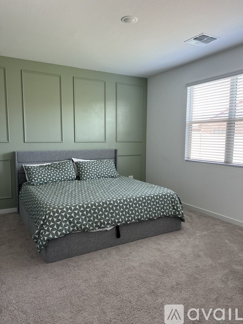 A bedroom with a bed, pillows, and a window with blinds.