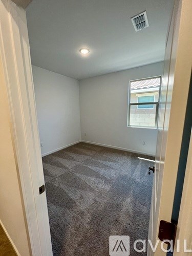 A room with a carpeted floor and a window.