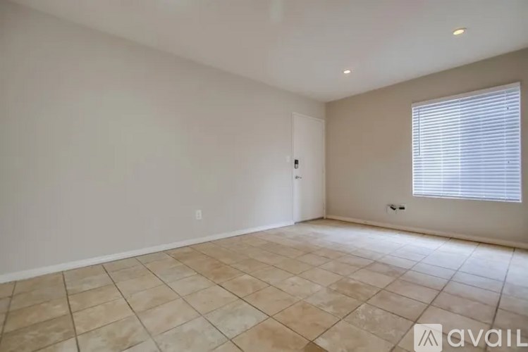 A room with beige tiled flooring and a window with blinds.
