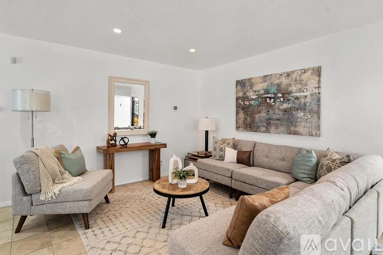 A living room with a grey couch, a wooden table, and a painting on the wall.