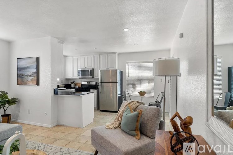 A living room with a grey couch and a kitchen in the background.