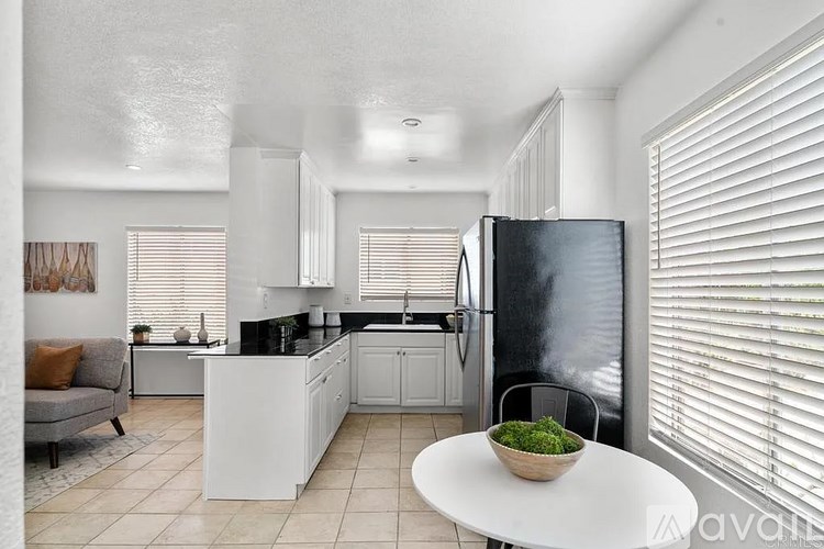 A modern kitchen with a black refrigerator and white cabinets.