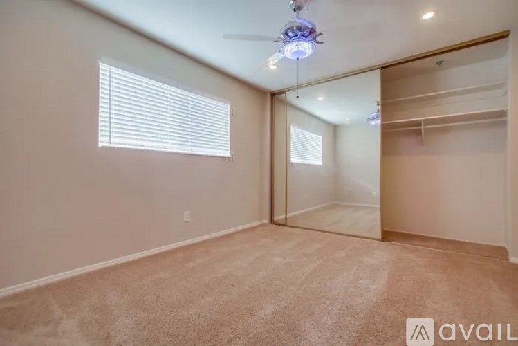 A room with a carpeted floor, a ceiling fan, and a sliding door.