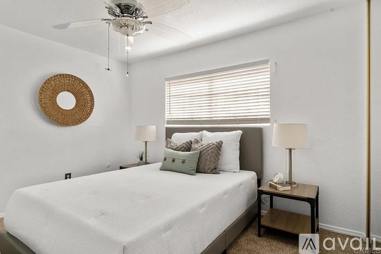 A bedroom with a white bed and a ceiling fan.