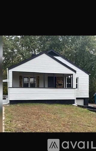 A white house with a black roof is available for sale.
