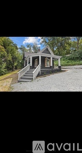 A small house with a porch is surrounded by trees.