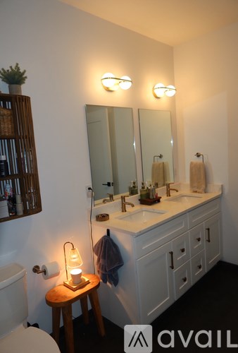 A bathroom with a toilet, sink, mirror, and a small table with a candle on it.
