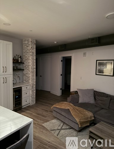 A living room with a grey couch and a white kitchen area.