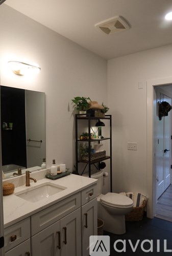 A bathroom with a sink, mirror, toilet and shelves.