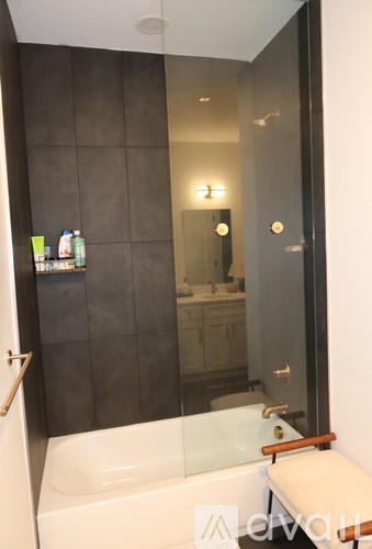 A modern bathroom with a white bathtub and a glass shower door.