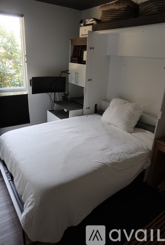 A bed with a white sheet and two pillows in a room with a window.