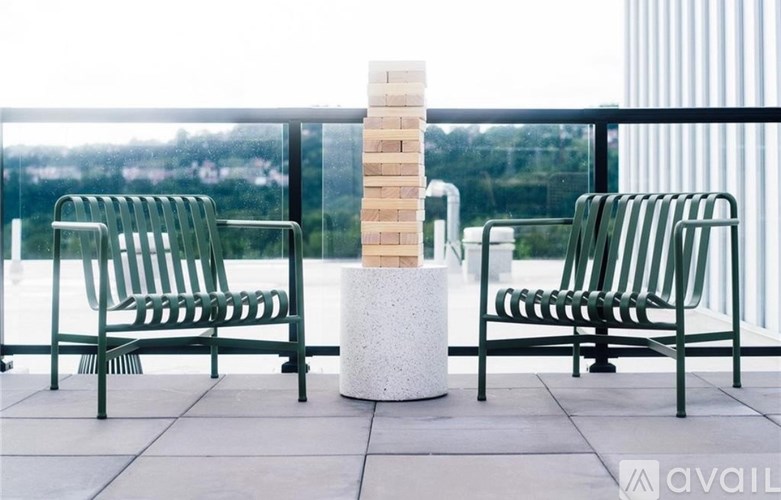 Two chairs are on a balcony with a stack of bricks in the middle.