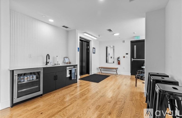 A modern kitchen with a wooden floor and a black fridge.