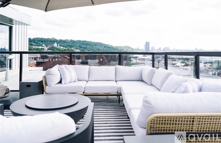 A white couch with a black table and a wicker chair on a balcony.