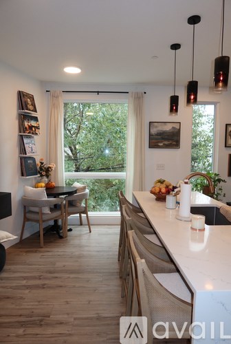 A modern kitchen with a dining area and a view of the trees outside.