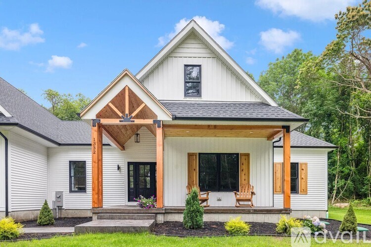 A white house with a brown roof and a porch.