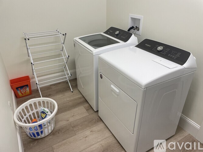 A laundry room with a washer and dryer, a basket with clothes, and a ladder.