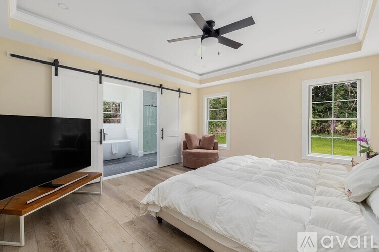 A bedroom with a bed, a television, and a sliding glass door leading to a balcony.