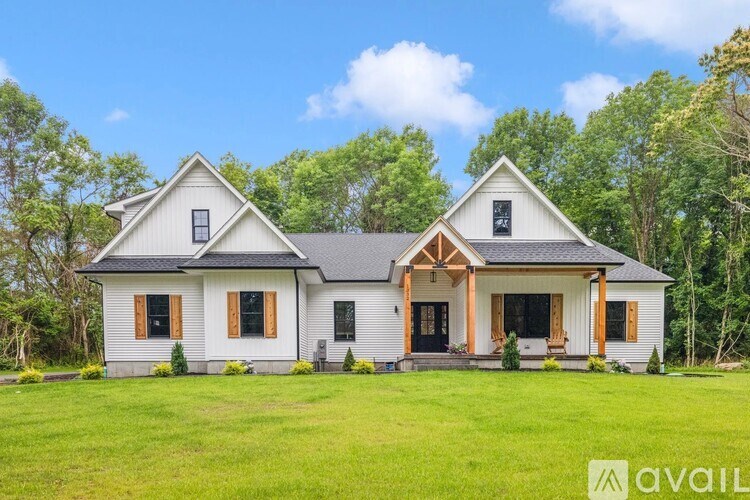A two-story house with a front porch and a balcony on the second floor.