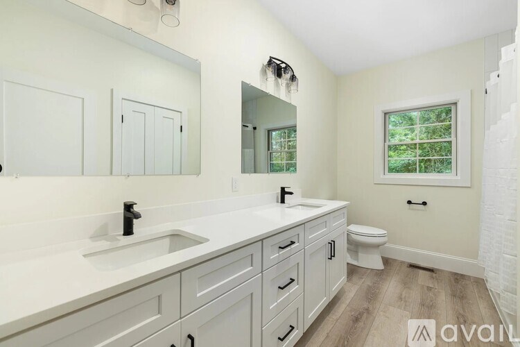 A bathroom with a white sink, toilet, and cabinets.