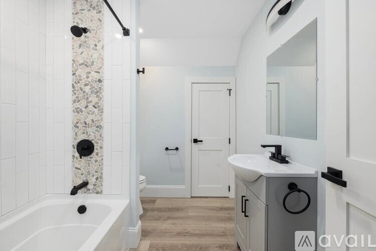 A bathroom with a white tub, sink, and a stone column.