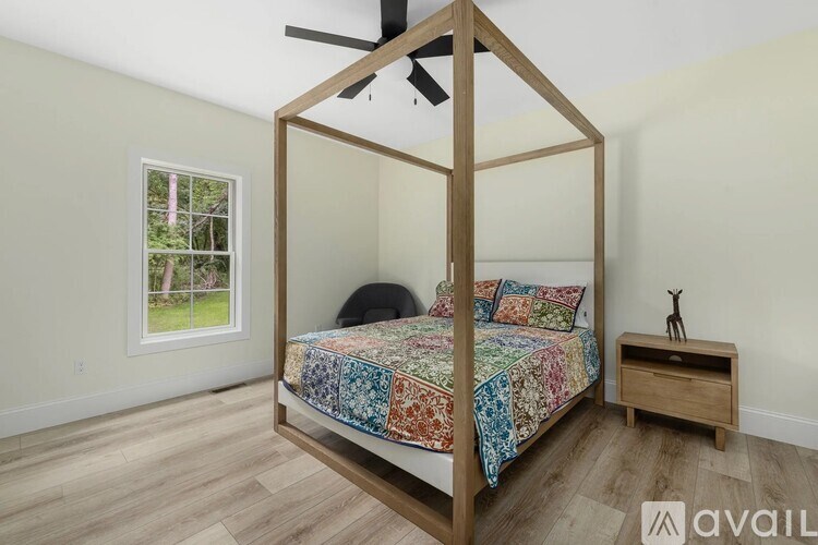 A bedroom with a four-poster bed and a ceiling fan.